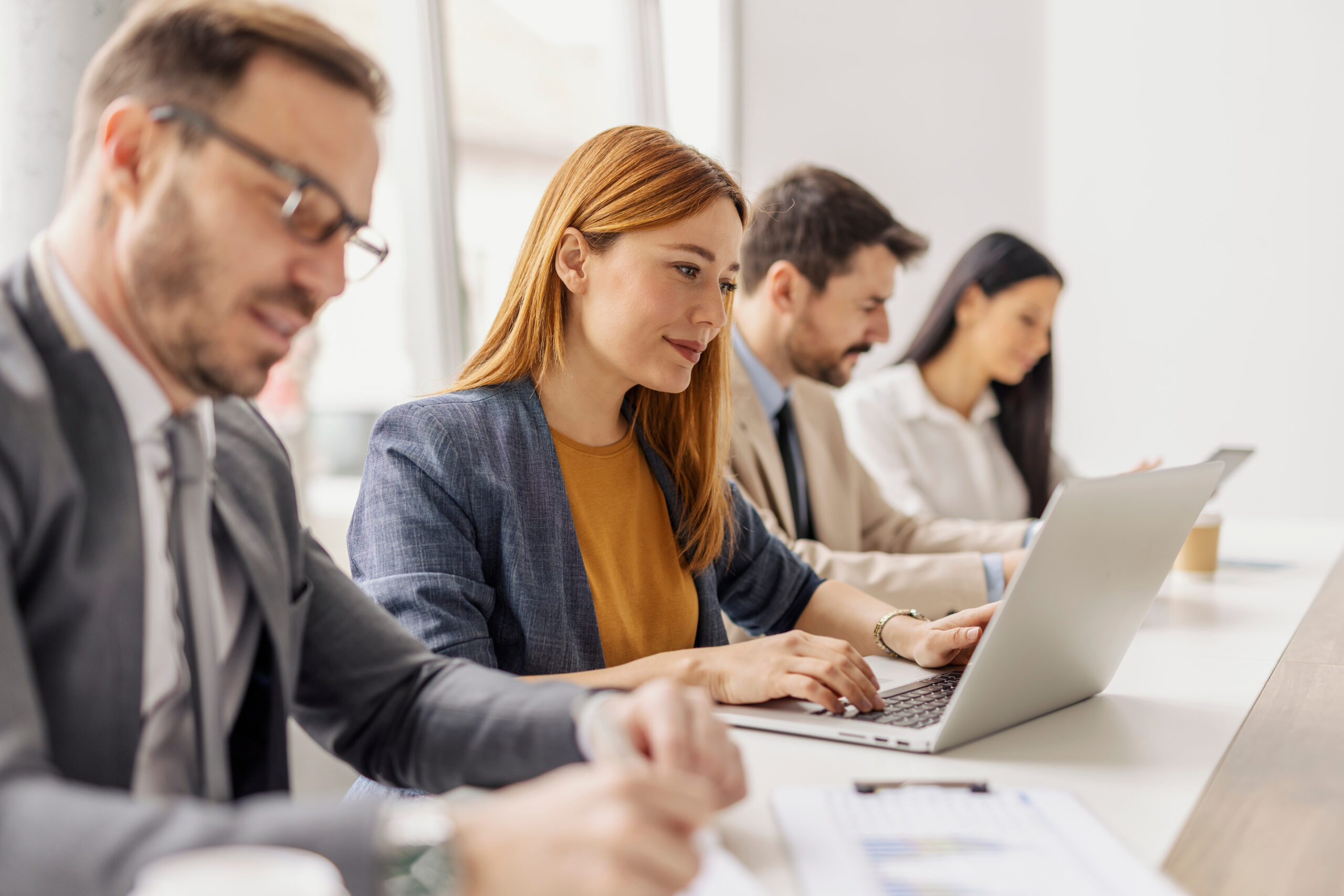 Mitarbeitende arbeiten im Rahmen eines Informationssicherheits Managementsystems konzentriert an Laptops.
