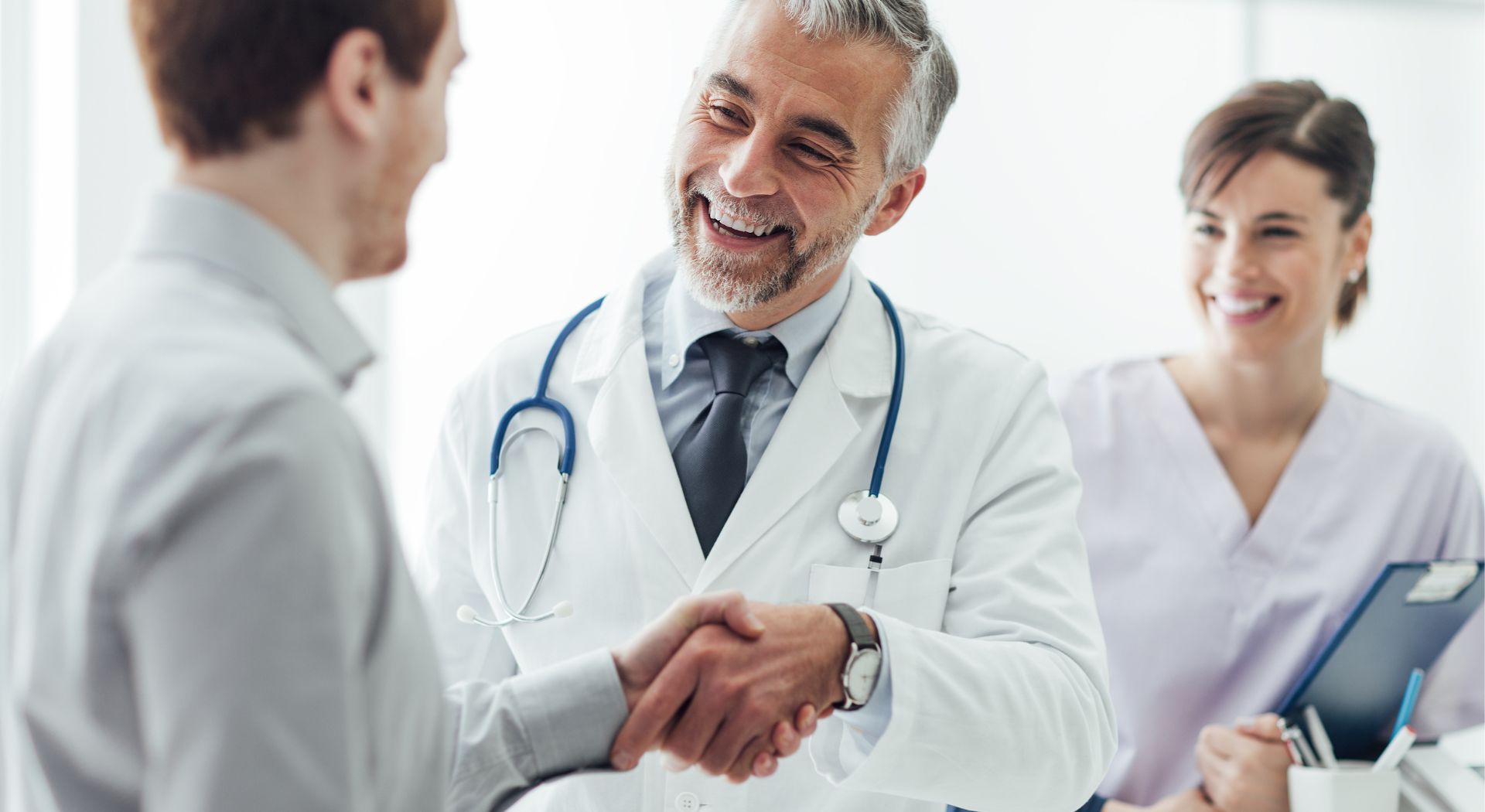 Arzt begrüßt einen Patienten per Handschlag und steht für Vertrauen, Datenschutz und Cybersicherheit im Gesundheitswesen.