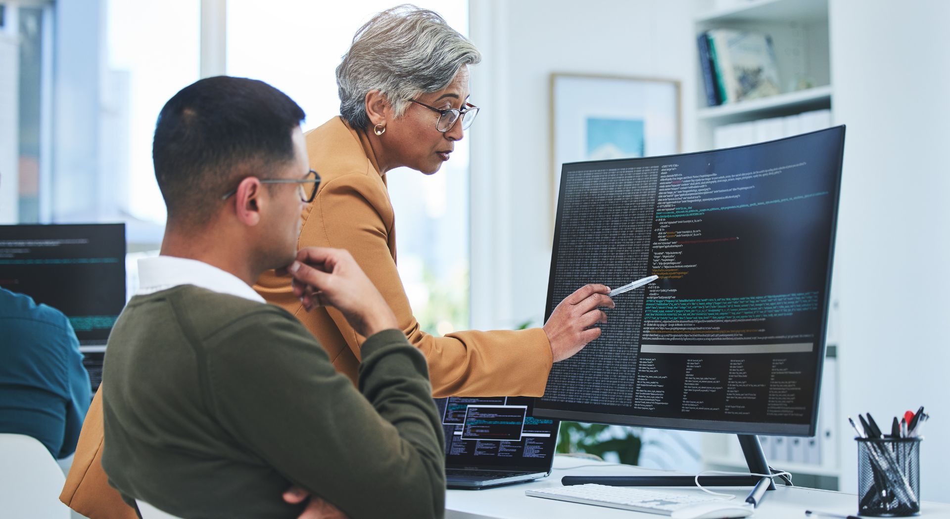 Ein Team analysiert Quellcode am Monitor im Rahmen eines IT-Audits und einer Zertifizierungsprüfung zur Stärkung der Cybersecurity und Compliance.