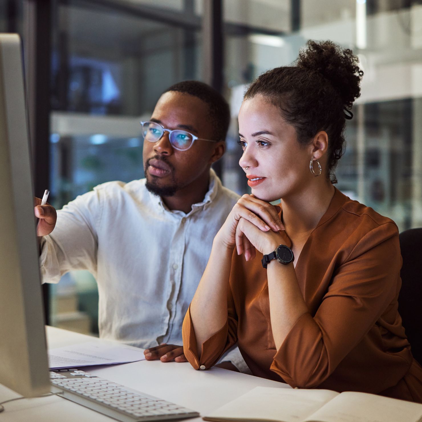 Zwei Mitarbeitende analysieren gemeinsam am Monitor Ergebnisse eines Schwachstellenscans zur IT-Sicherheitsanalyse und zum Schwachstellenmanagement im Unternehmen.