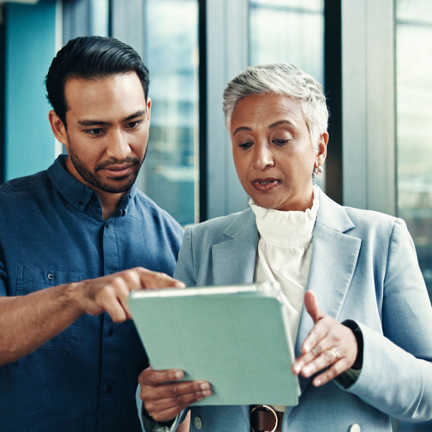 Zwei Fachkräfte prüfen gemeinsam ein Tablet zur Gap Analyse in der IT-Sicherheitsberatung und bewerten Compliance- sowie Sicherheitslücken.