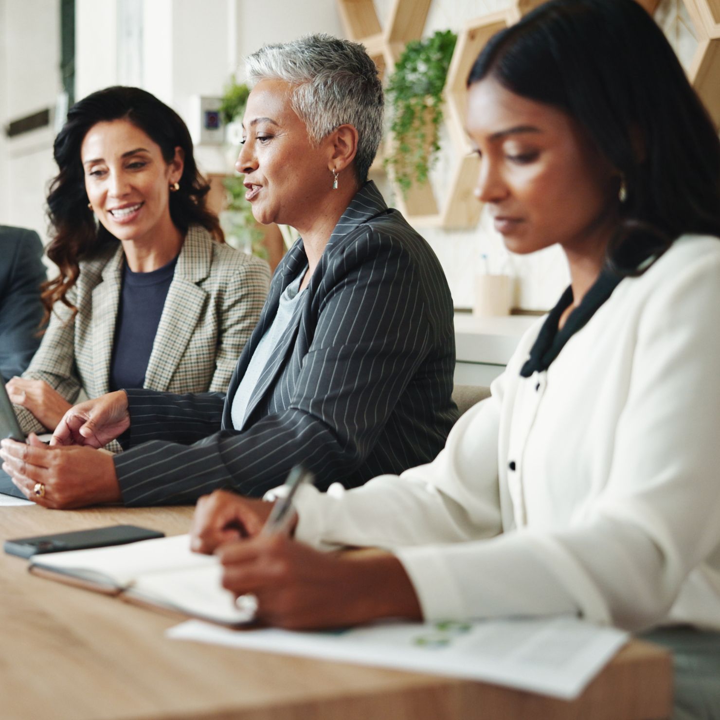 Ein Team bespricht ein Informationssicherheits Managementsystem am Tablet in einem Unternehmensmeeting.