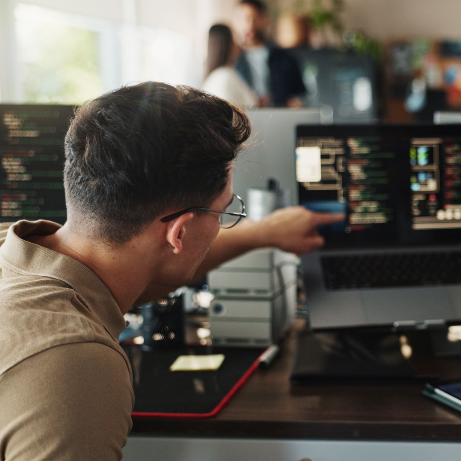 IT-Team analysiert Ransomware-Code am Laptop und bespricht neue Erpressungsmethoden zum Schutz des Unternehmens.
