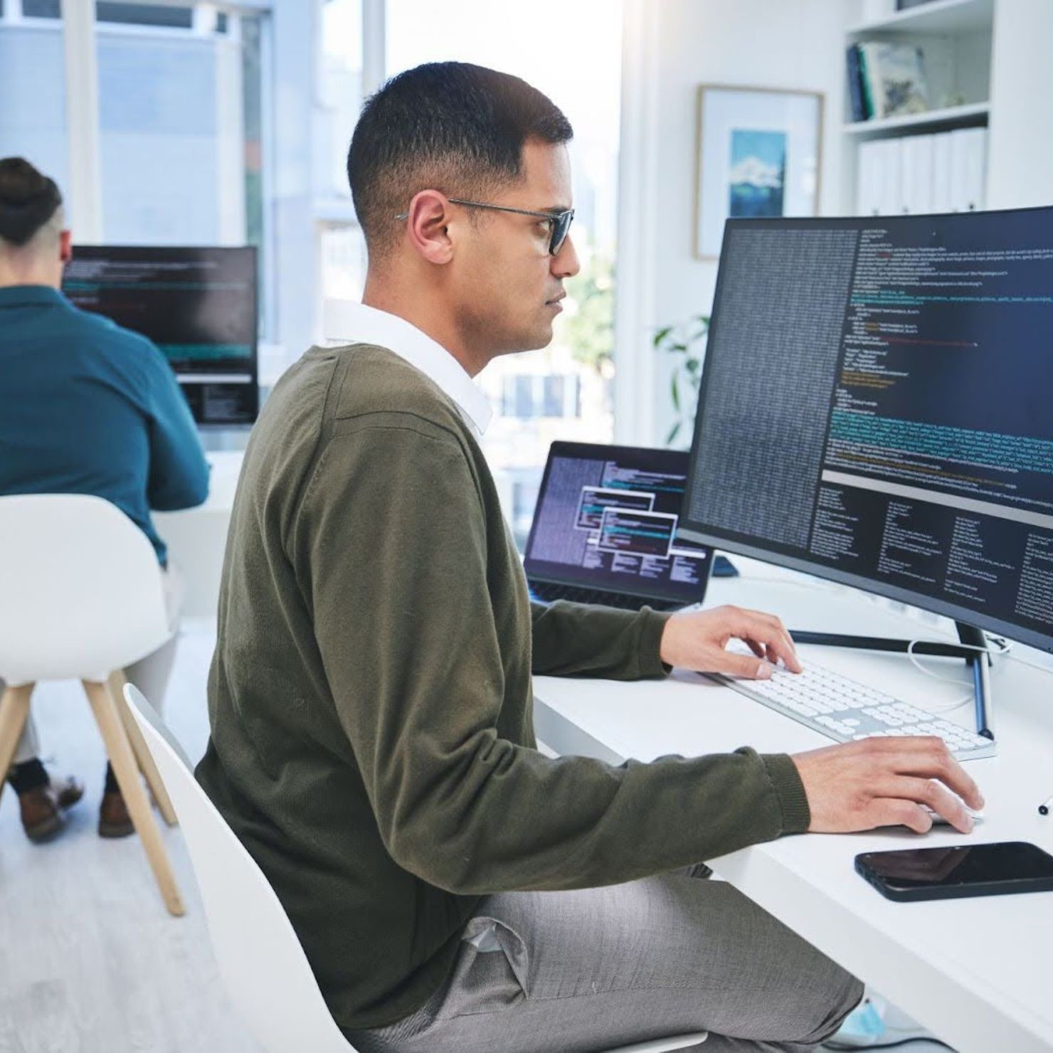 Mitarbeiter überwacht sicherheitsrelevante Systeme und Code auf einem großen Monitor zur Absicherung kritischer Infrastrukturen.