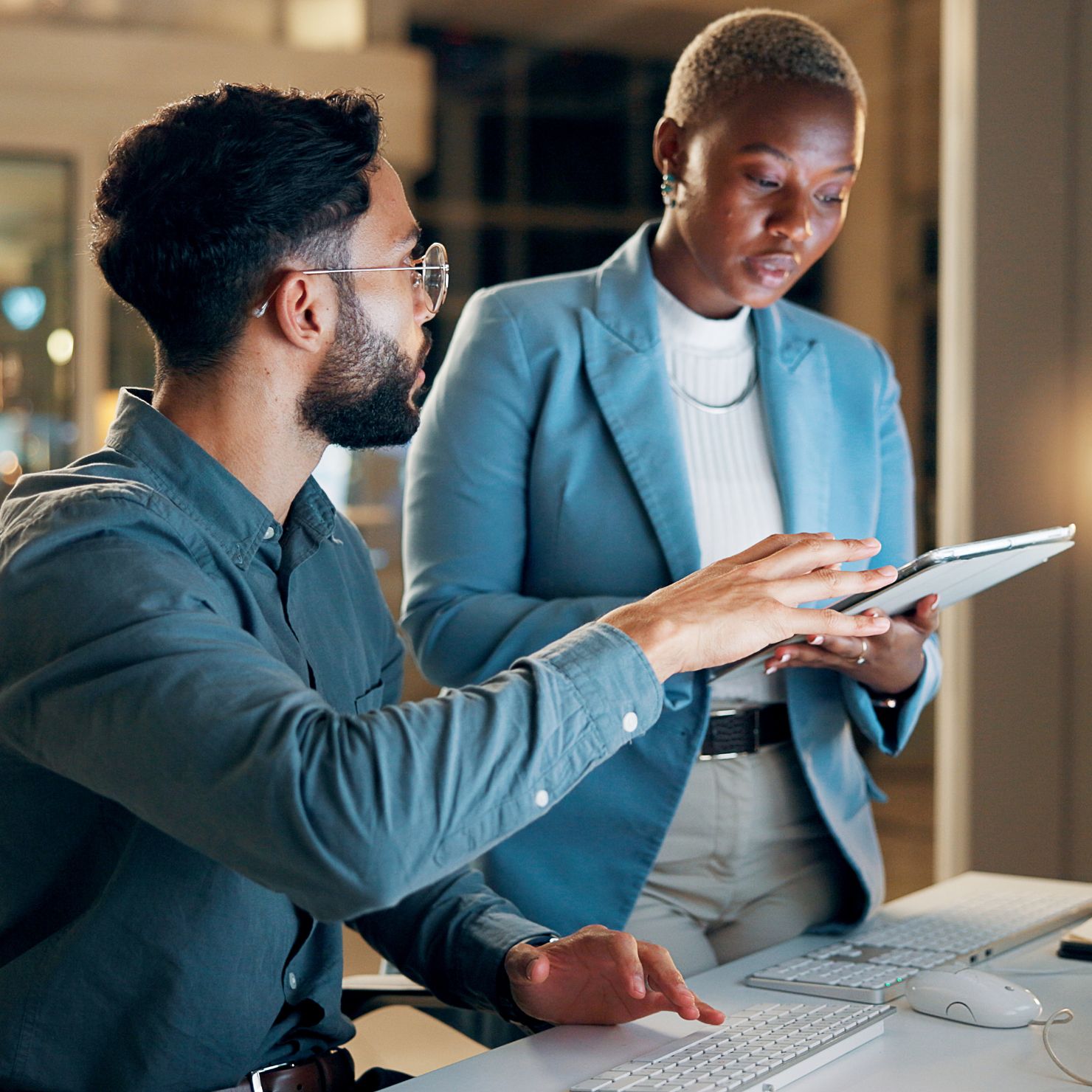 Kollegen besprechen Security Awareness in hybrider Arbeitswelt und prüfen am Tablet sichere Arbeitsabläufe am Büro-PC.
