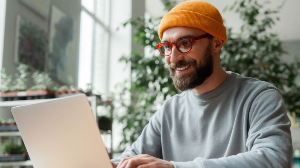 ann arbeitet am Laptop in heller Umgebung mit Pflanzen im Hintergrund
