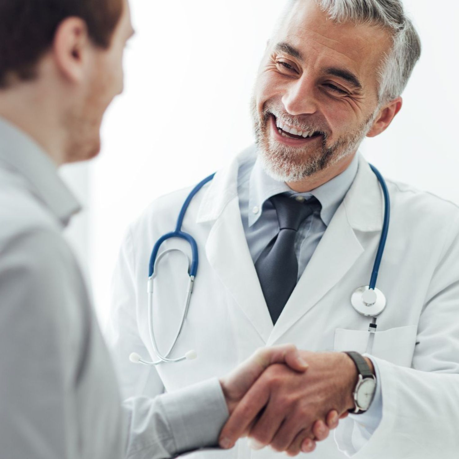 Arzt begrüßt einen Patienten per Handschlag und steht für Vertrauen, Datenschutz und Cybersicherheit im Gesundheitswesen.