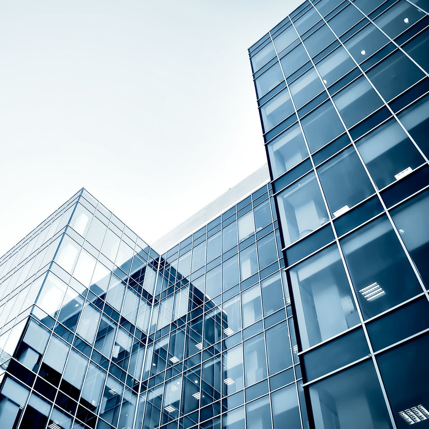 Moderne Bürogebäude mit Glasfassade in Froschperspektive – symbolisches Motiv für Unternehmenskompetenz, Struktur und Professionalität.