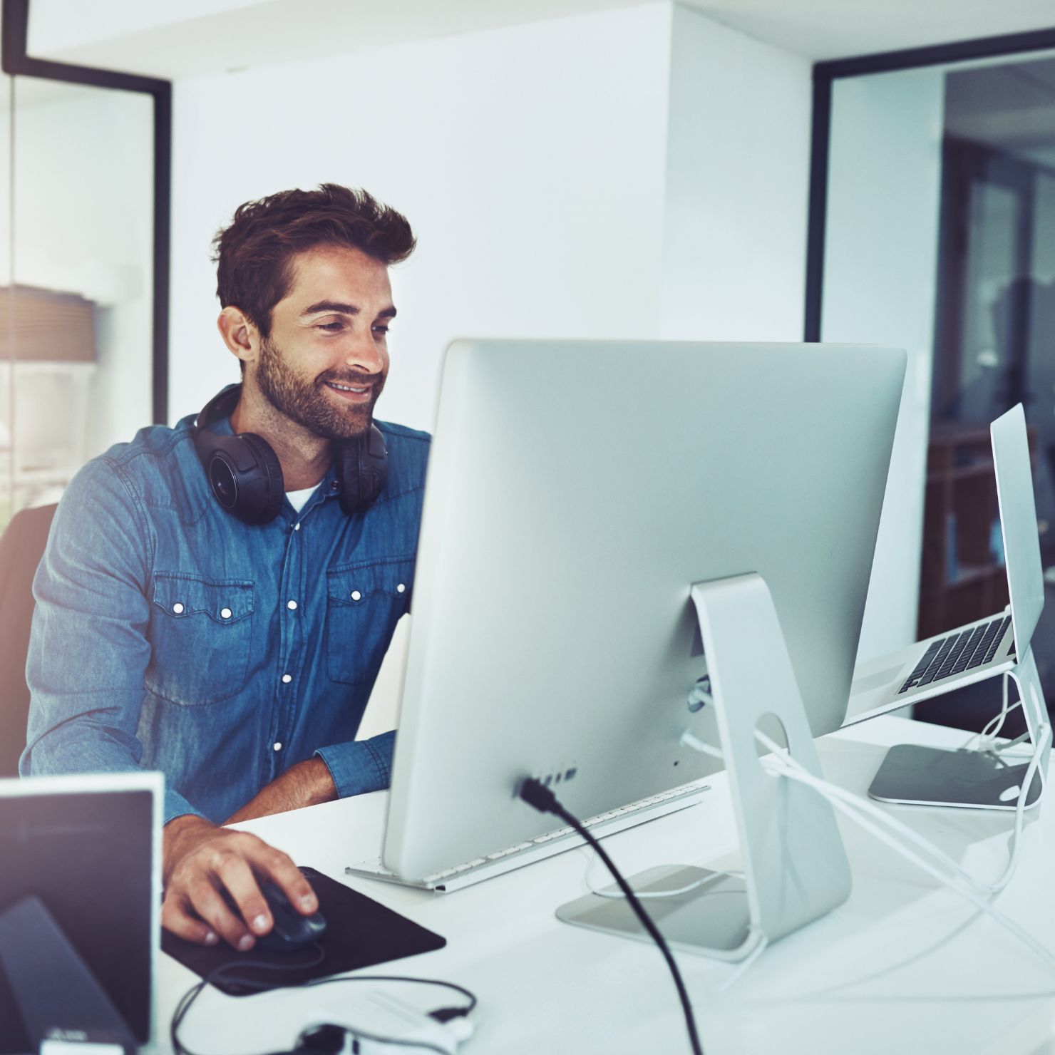 Ein IT-Mitarbeiter arbeitet am Desktop-PC im Büro und überwacht digitale Prozesse sowie IT-Sicherheitslösungen.