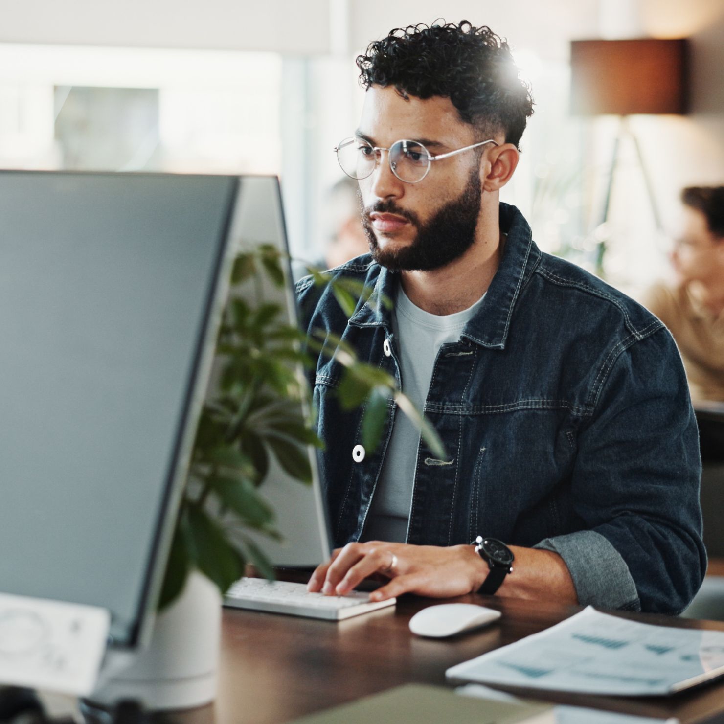 Mitarbeiter beobachtet konzentriert einen Monitor im Büro und steht sinnbildlich für aktive Angriffserkennung und Managed Detection and Response.