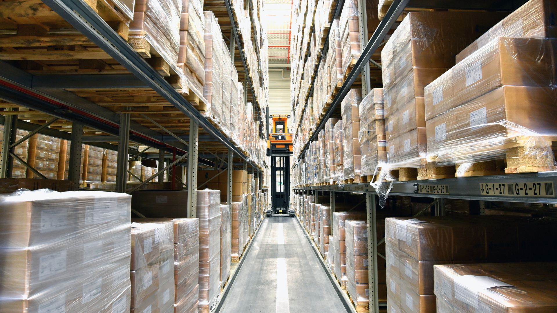 Logistiklager mit Warenpaletten steht sinnbildlich für 24/7 Cyber Defense und IT-Sicherheitsmonitoring im Produktionsumfeld.